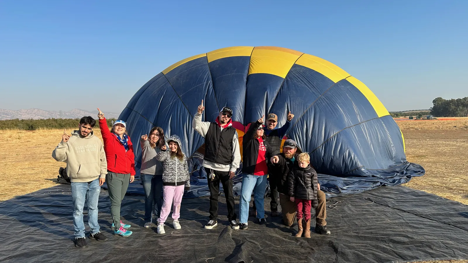 Multi-generation group posing with a hot air balloon after landing