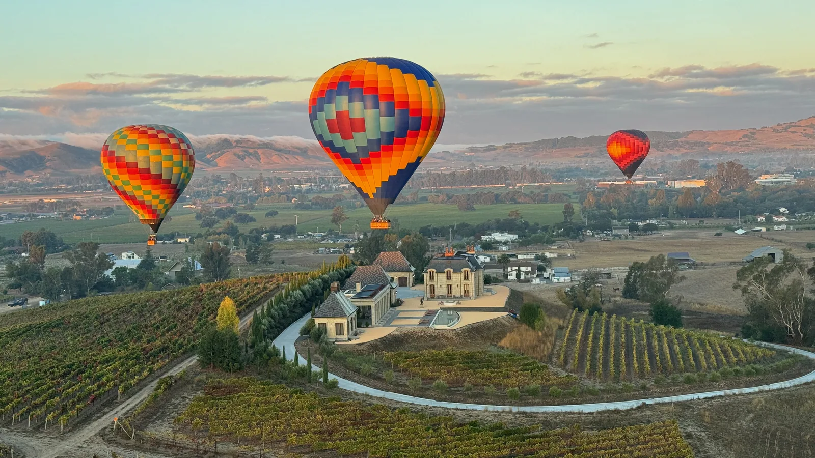 Hot air balloon rising over Sonoma Valley vineyards at sunrise, a short drive from Santa Rosa
