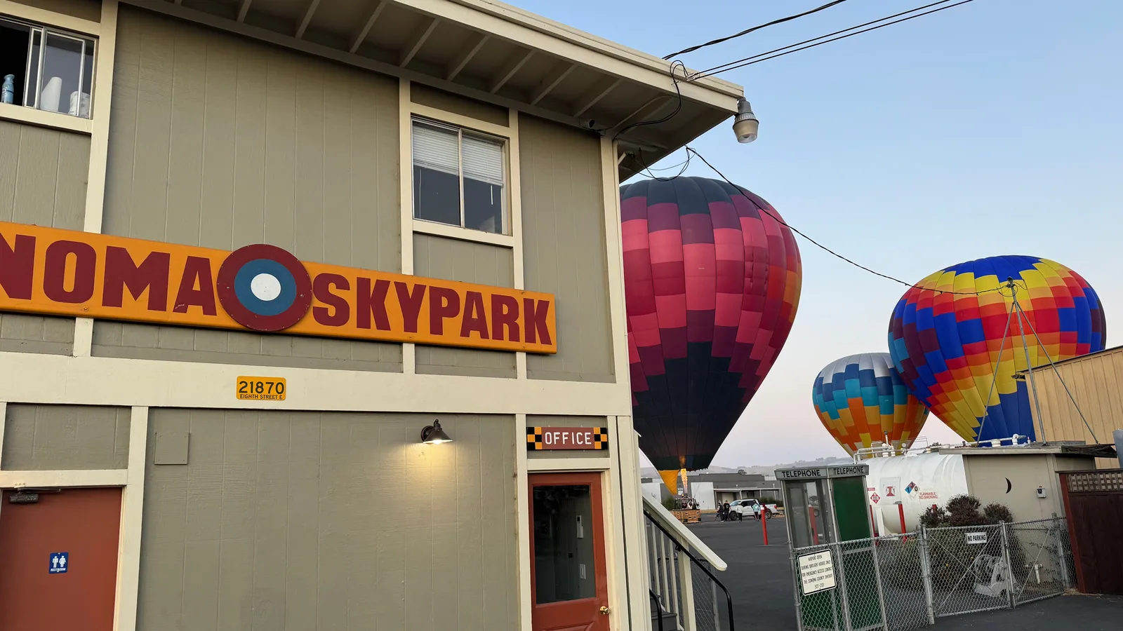 Hot air balloons inflated in front of the Sonoma Skypark building at dawn, the check-in point for East Bay guests