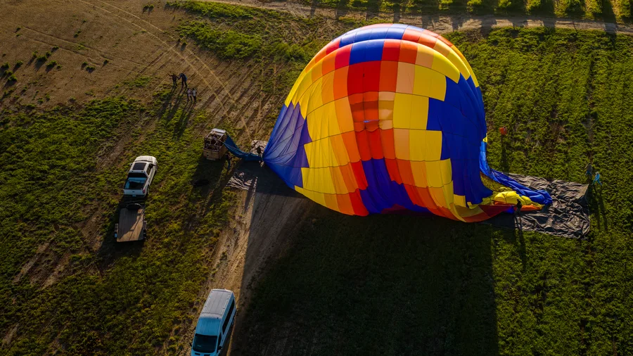 Chase crew vehicles beside a deflating hot air balloon in a green Sonoma field