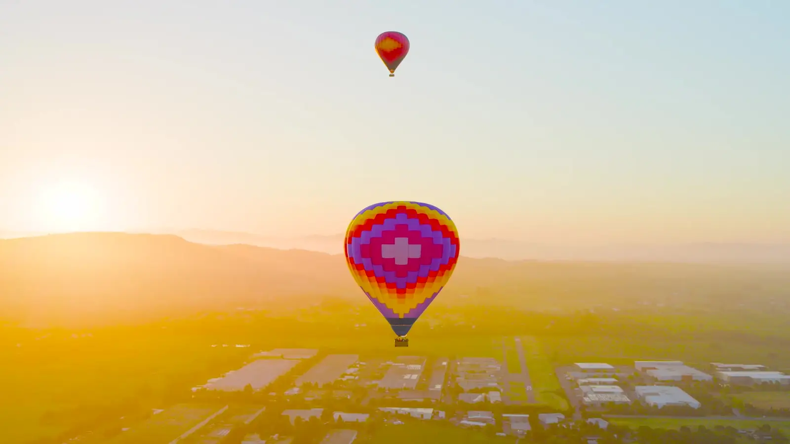 Hot air balloon drifting over Sonoma Valley vineyards at sunrise