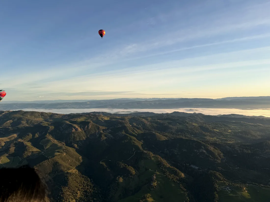 Balloons floating above mountain ridges and a sea of morning fog